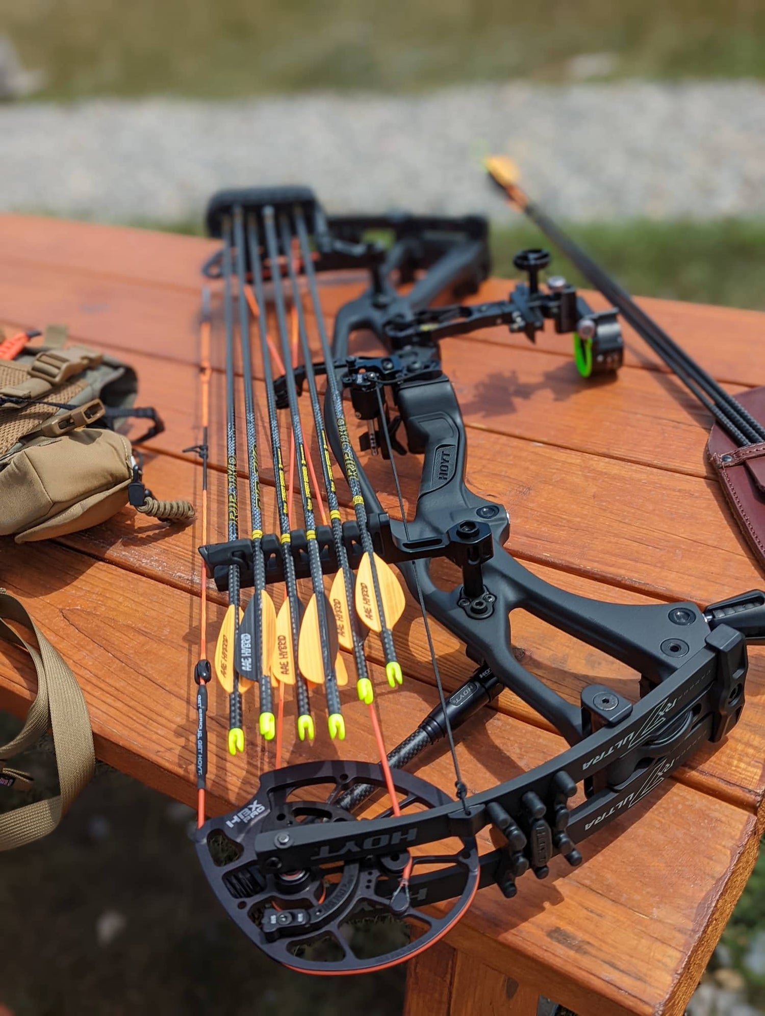Black compound bow with arrows and quiver on wooden table